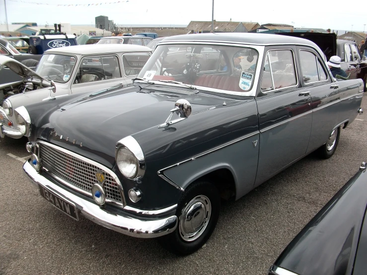 a classic car in a parking lot, with other cars around it