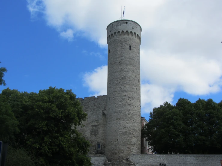 a gray brick tower that is surrounded by trees