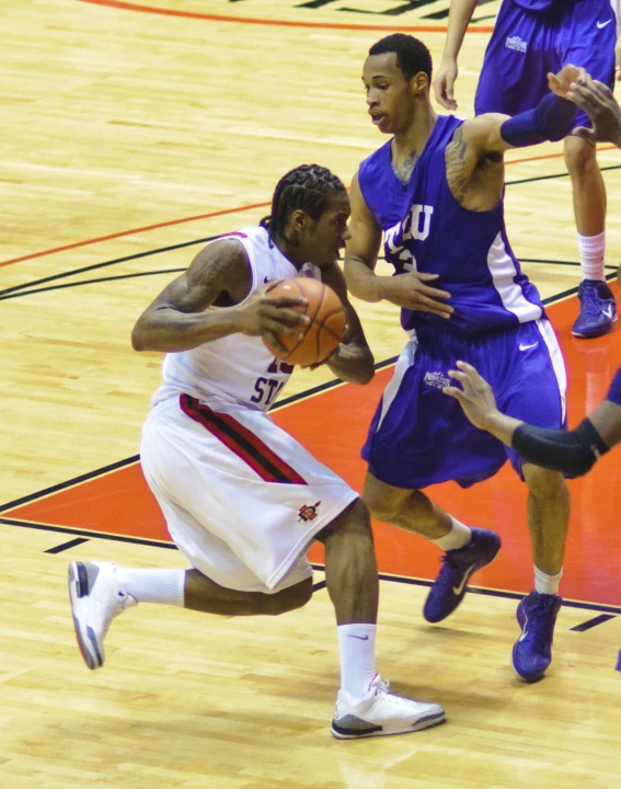 basketball player running towards another player with a ball