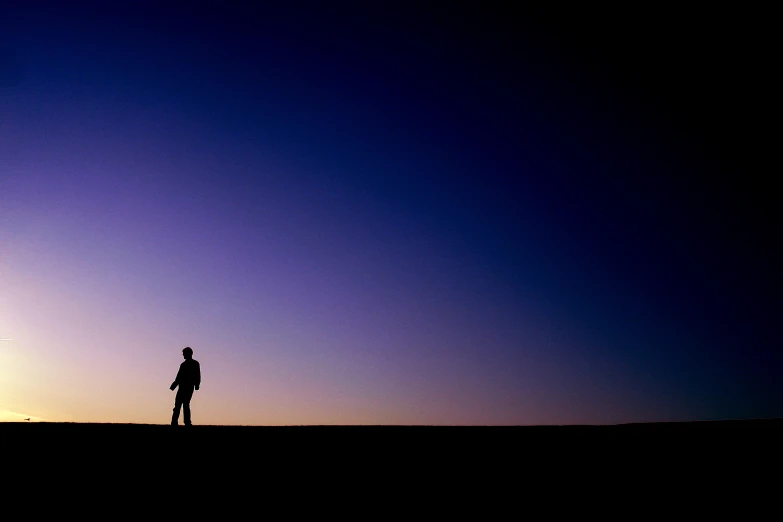 a man standing on top of a desert under a purple sky