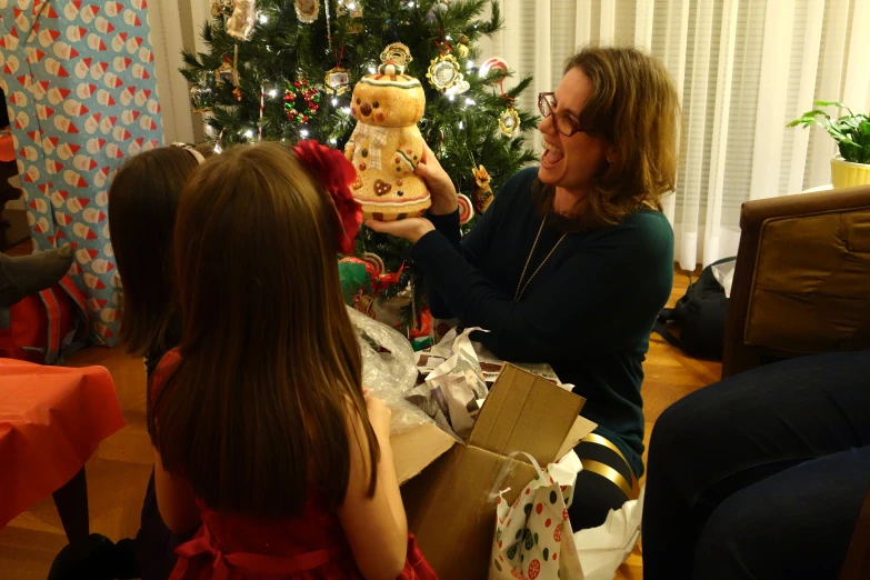 a woman is holding up a bear next to a christmas tree