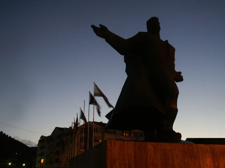 a statue at dusk with other flags in the background