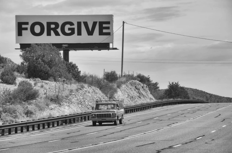 a black and white image of the word forgve on the side of a highway