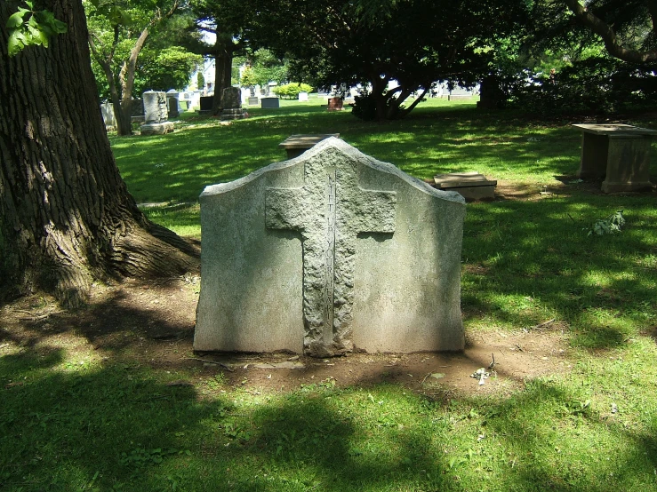 a cross sits between two headstones in the grass