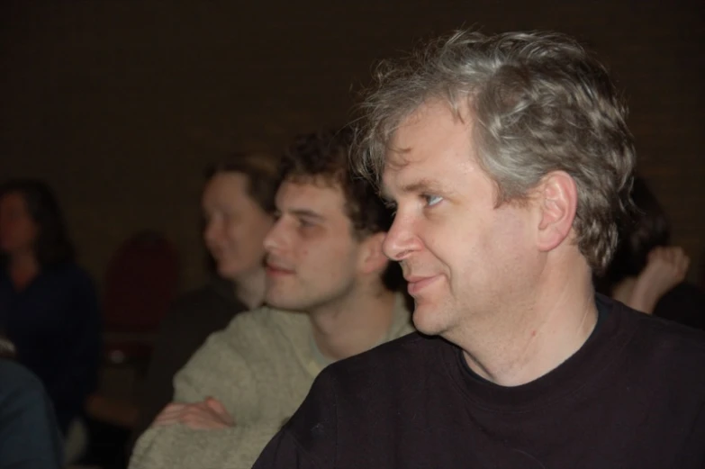 three men sitting and watching soing with their eyes wide open