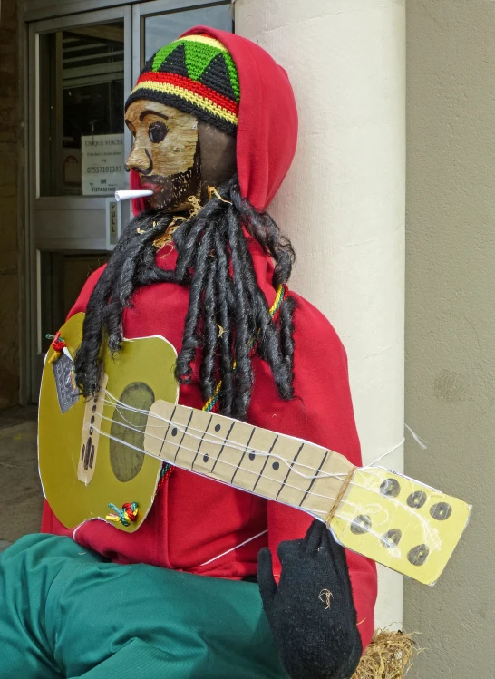 a man with dreadlocks wearing a red jacket holds an electric guitar