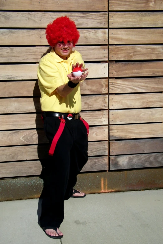 a person dressed up like the red headed clown holding a tennis ball