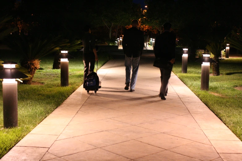 people are walking down the path at night