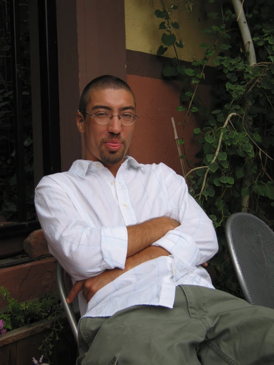 a man sitting in a chair outside next to a building