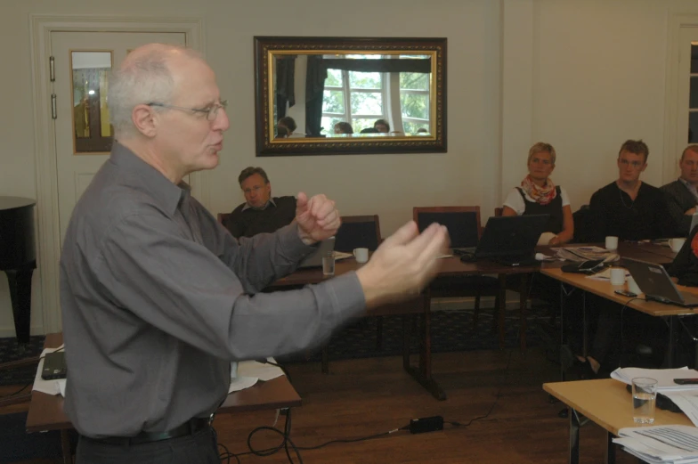 a man holding up his hands in front of other people sitting at tables