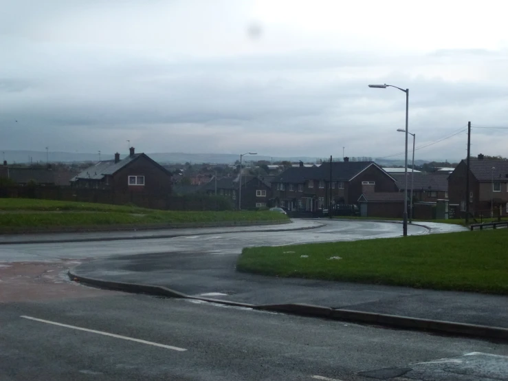 a rain covered road that has some houses on the side