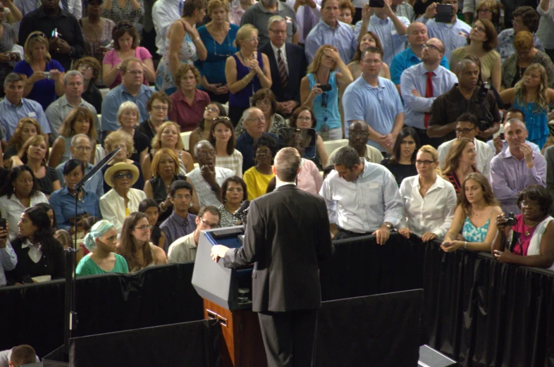the man stands at a podium as others listen