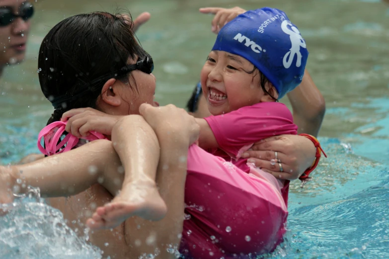 two s swimming in a pool with a cap on