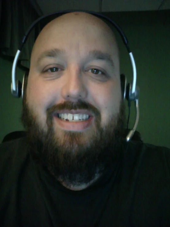 man wearing headphones, smiling, while talking on his phone