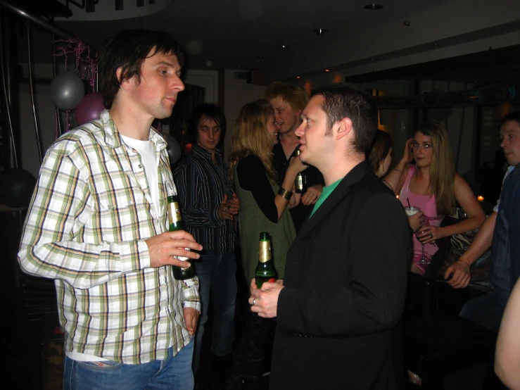 two men standing and drinking wine in a crowded room