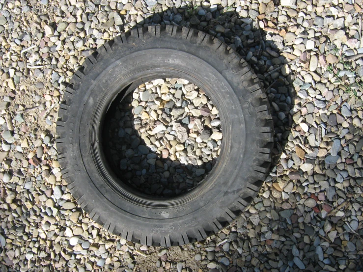 a tire is laying on the ground beside some gravel