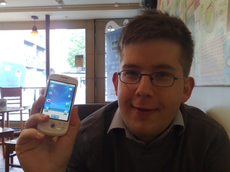 a man holds up an iphone while posing for the camera