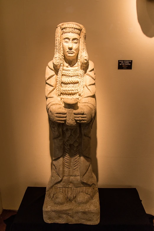 a statue sits in a room with a white wall