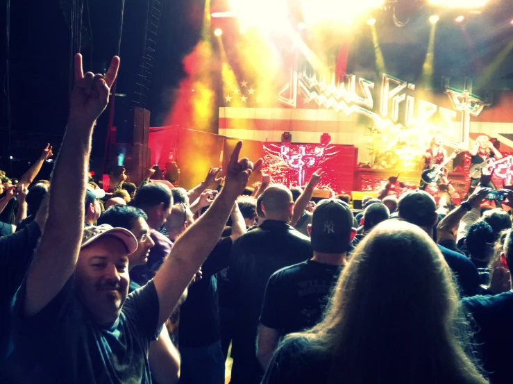 a crowd of people in a concert with their arms up