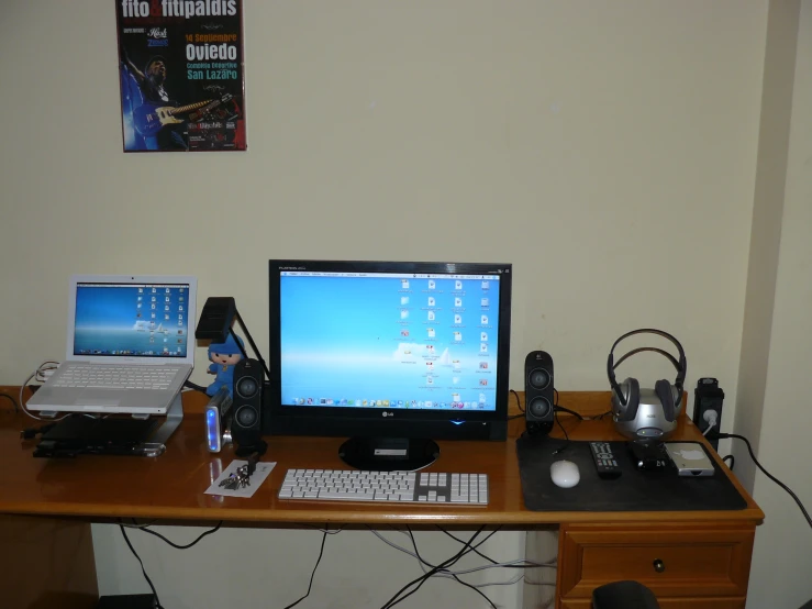 a small wooden desk with two laptops and a computer monitor on top