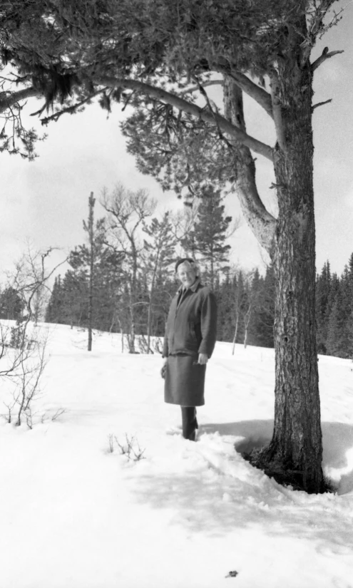 an old man standing next to a tree on the snow