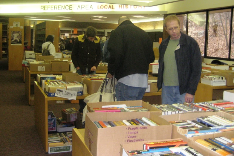 men are looking at books for sale at a liry