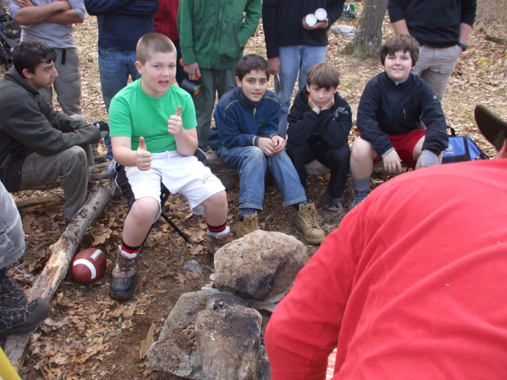 several boys are sitting on some rocks and smiling at someone