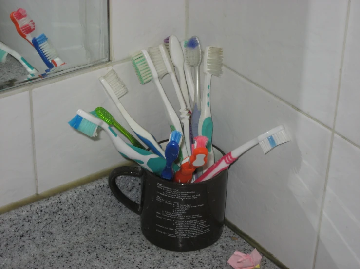 there are many toothbrushes in the cup on the bathroom counter