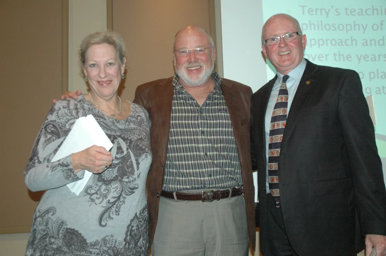 two people smile while posing with a man in a suit