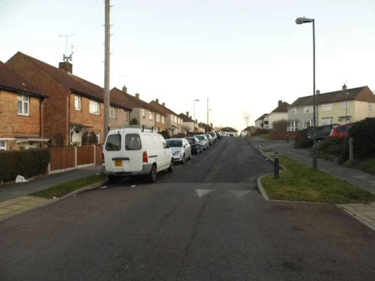 a white van driving down a road next to tall houses