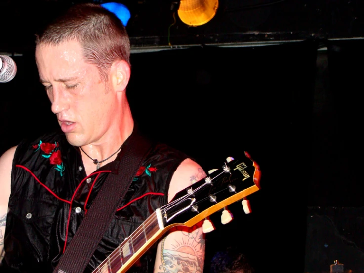 a man with tattoos holding a guitar