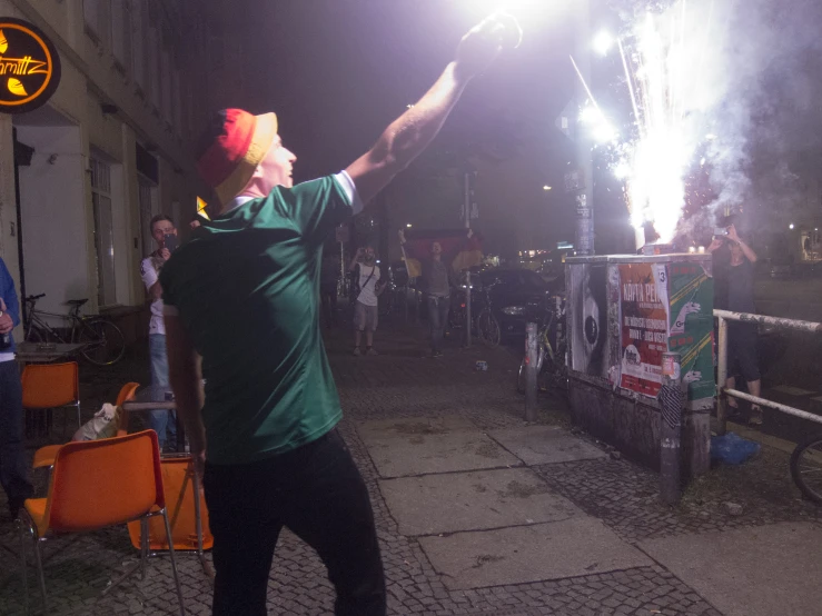 a man standing on top of a sidewalk holding a firework