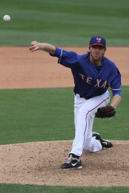 a man in a blue and white uniform throwing a baseball