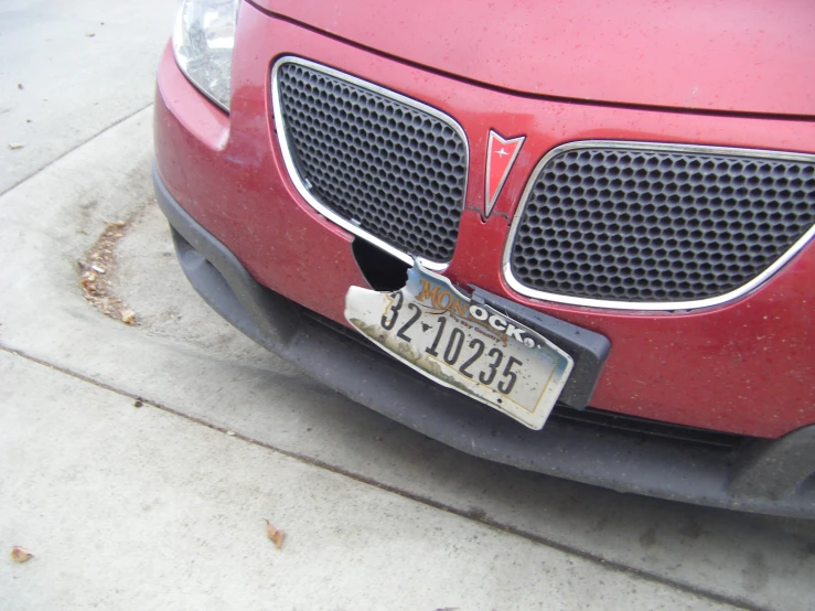 the red car is parked on the curb with its license plate