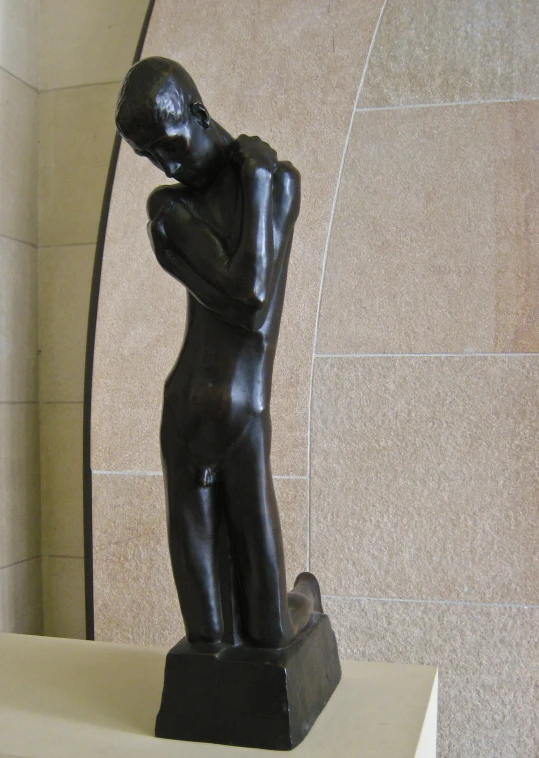 a statue of a boy sitting down on a wall