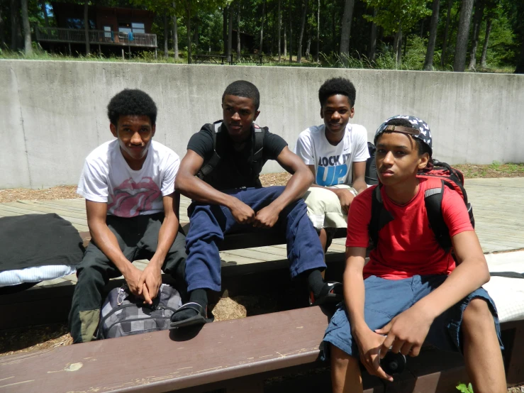 four young people sitting on a bench with one holding his purse