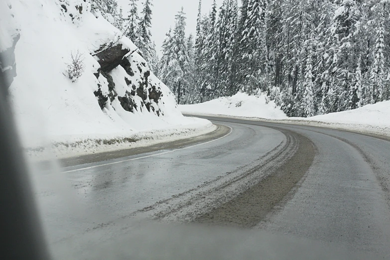 a road lined with snow on both sides by a large rocky cliff