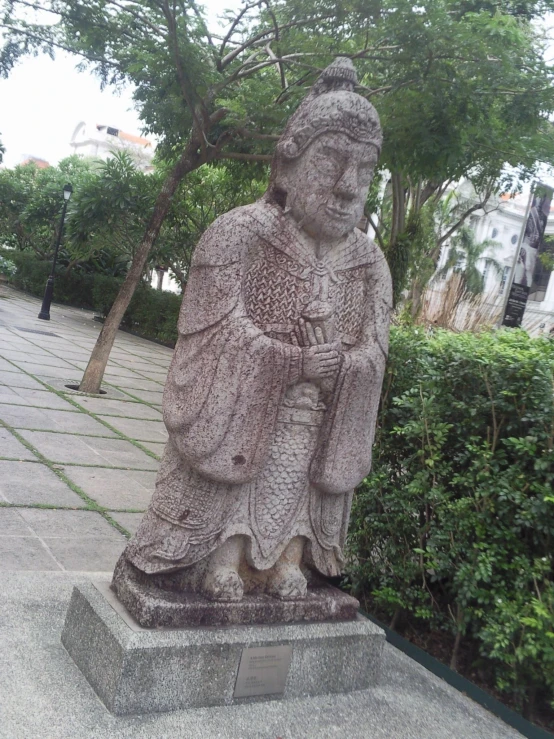 a statue of an old monk is sitting on the sidewalk