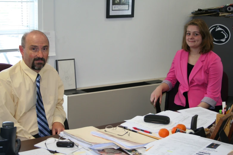 a man and woman sitting at a desk with paperwork