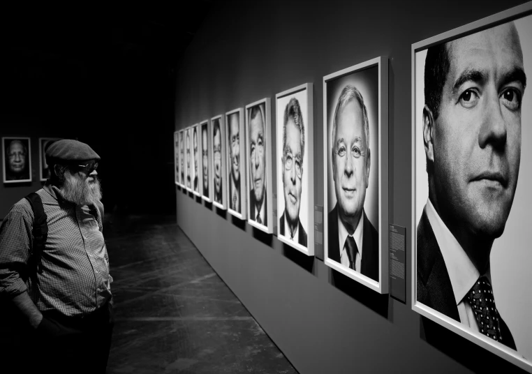 the man is standing by the large black and white portraits