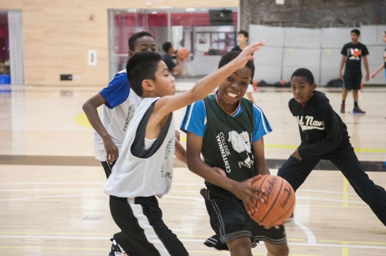 children in sports uniforms are playing basketball in the gymnasium