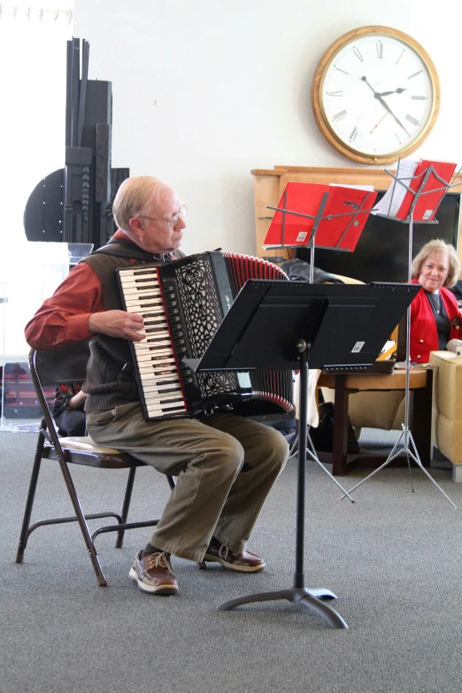 an older man sitting on top of a chair next to a piano