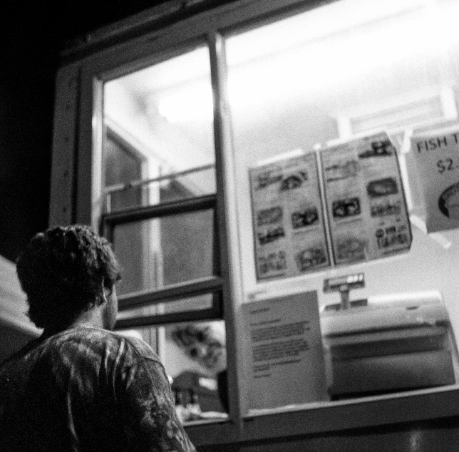 a man stands outside a store front looking at the sky