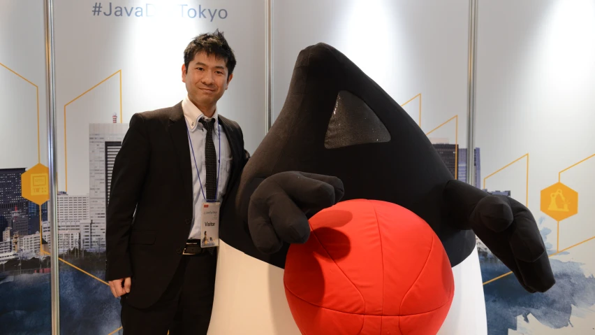 a man stands beside a big stuffed animal in a suit