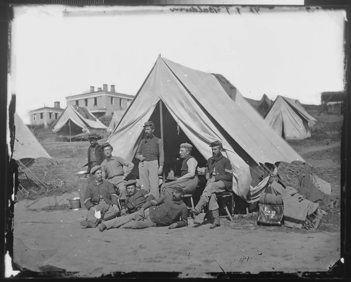 a black and white po of people sitting outside of a tent
