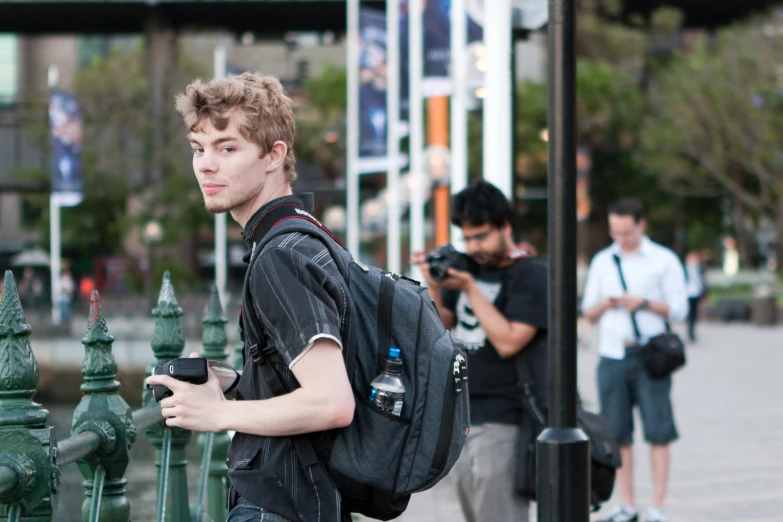 a young man holding his cell phone as he walks in front of green fire hydrants