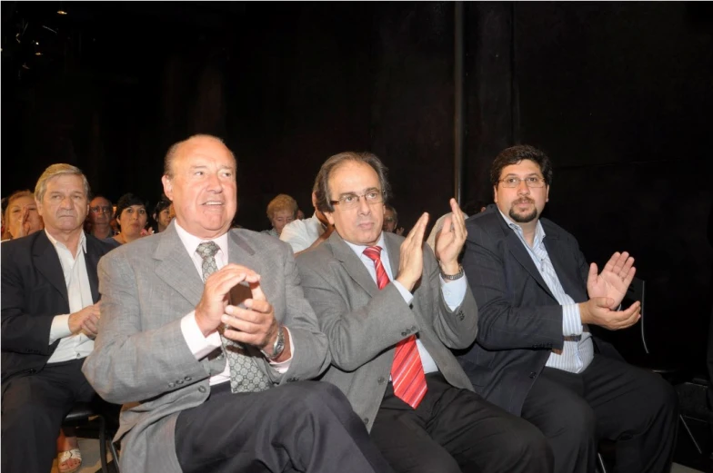 a group of men sitting in chairs clapping