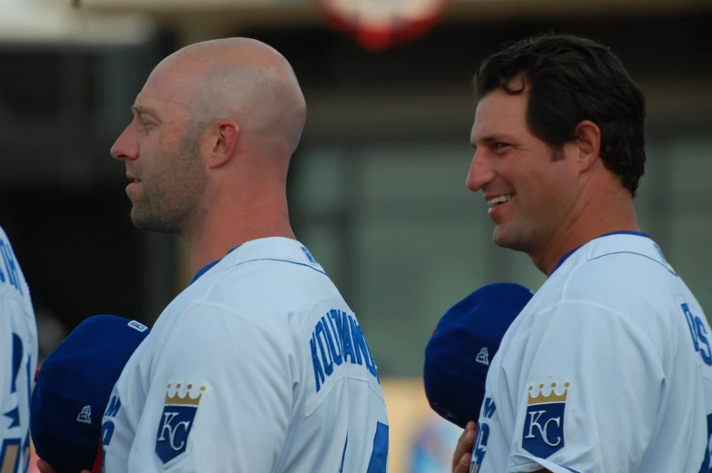 a man with bald head and other men standing around