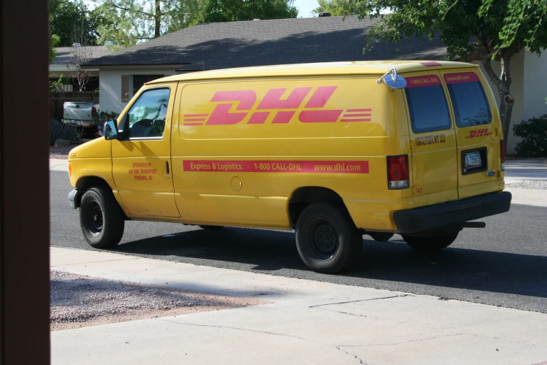 yellow van with red lettering on the side in front of a house