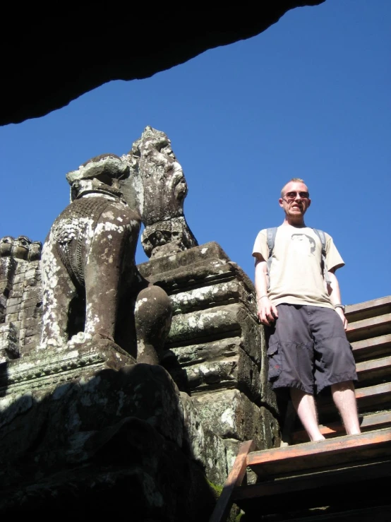 a man standing in front of a stone building with statues of elephants on top